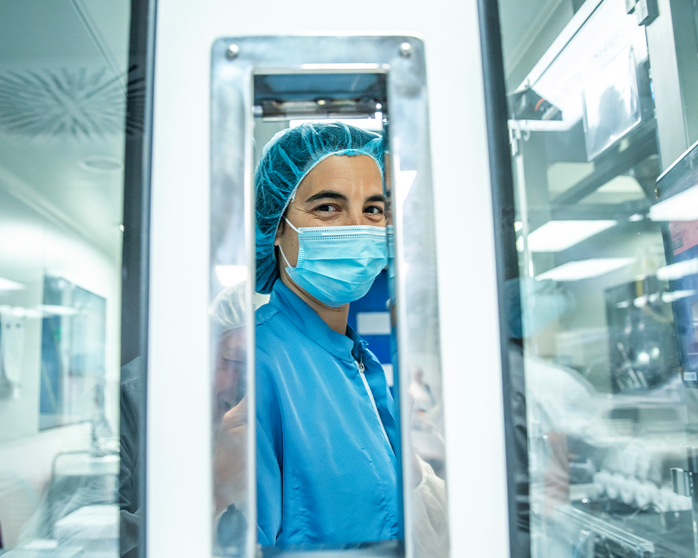 Una operaria especializada con mascarilla y vestimenta azul en una planta de producción industrial de la empresa Ferrer.