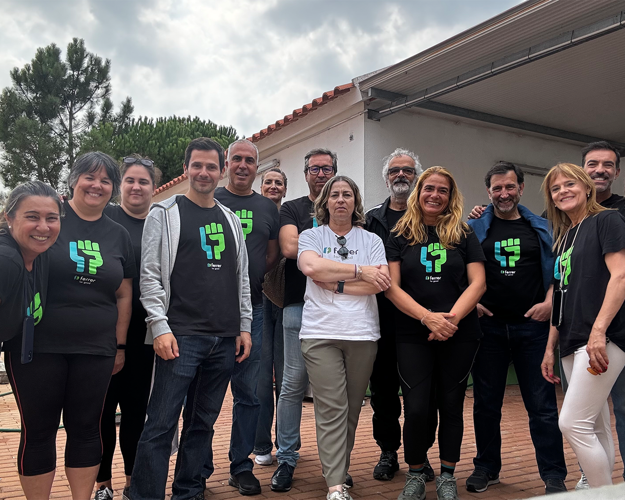 Ferrer team poses in a group during an outdoor corporate activity, wearing company T-shirts.