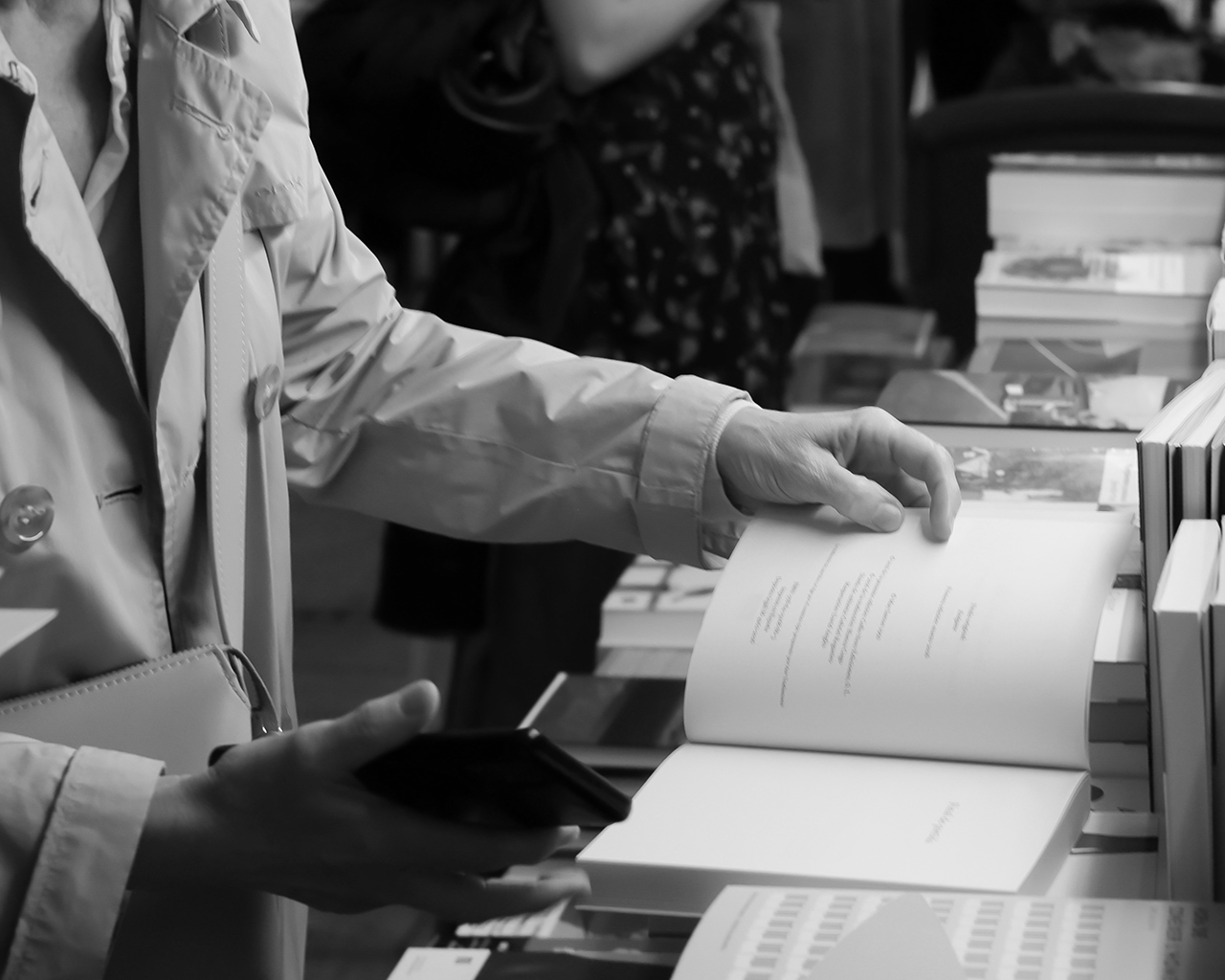 Una persona hojea un libro abierto en un mostrador literario durante un evento cultural de la Fundación Ferrer.