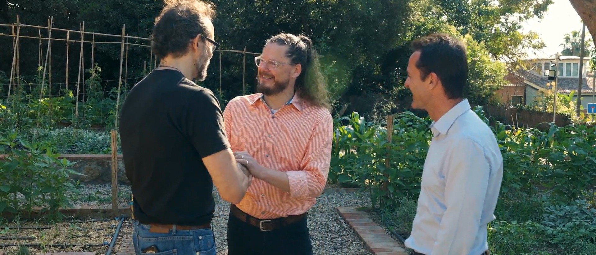Tres profesionales conversan en un huerto o jardín al aire libre durante una noticia de Ferrer sobre propósito con Matthew McCarthy.