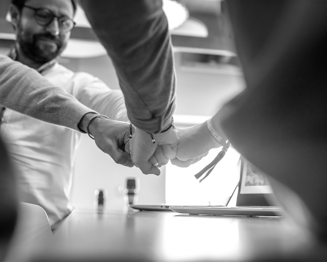Miembros del equipo directivo de Grupo Ferrer uniendo sus puños en una reunión de liderazgo corporativo y estrategia.
