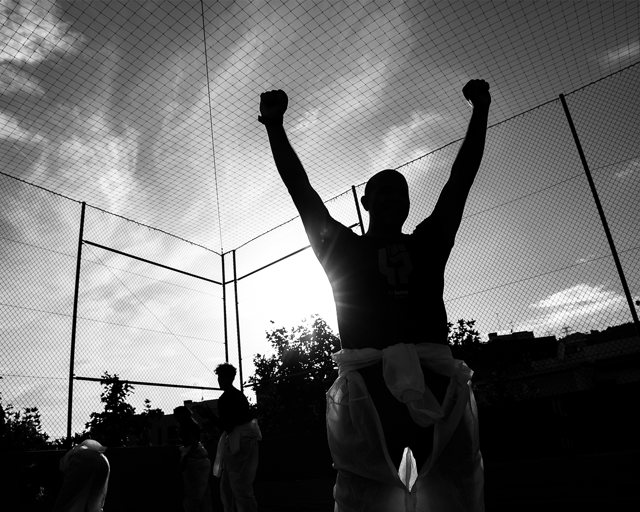 Silhouette of a Grupo Ferrer employee celebrating with his arms raised outdoors.