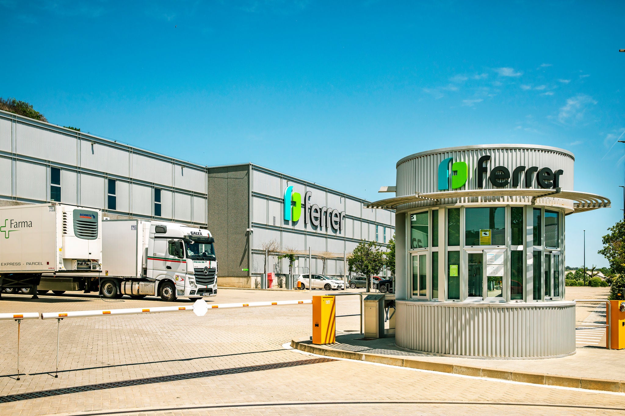 Centro logístico de Ferrer con acceso principal, camión de transporte y garita de seguridad con el logotipo de la compañía.