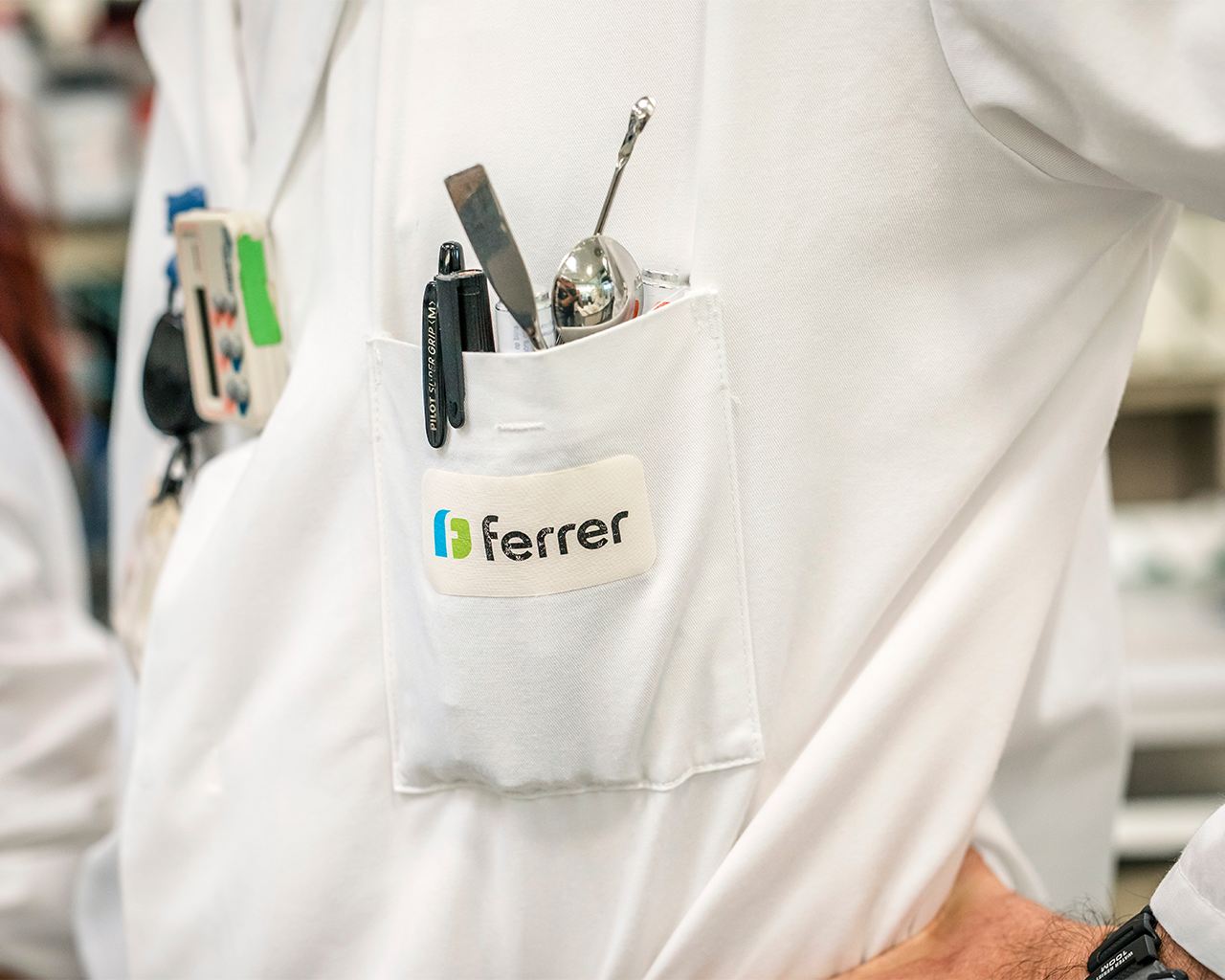 Primer pla de l' uniforme d' un científic al laboratori d' R + D de Ferrer amb el logotip corporatiu a la bata.
