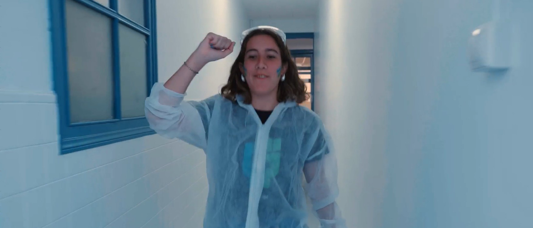 Profesional de Ferrer en un entorno de laboratorio o planta de producción, vestida con bata y equipo de protección, levantando el brazo en señal de energía o compromiso.