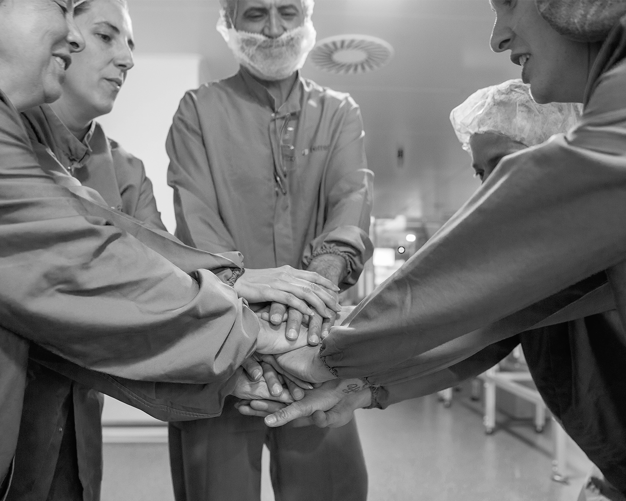 Team of professionals from the Ferrer company sharing a gesture of camaraderie and union in the production plant.