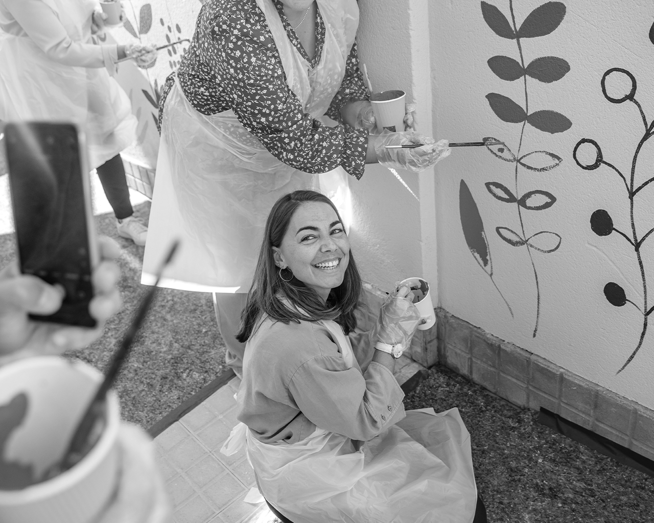 Team of volunteers from the Ferrer company collaborating in the creation of an artistic and sustainable mural during a community day.