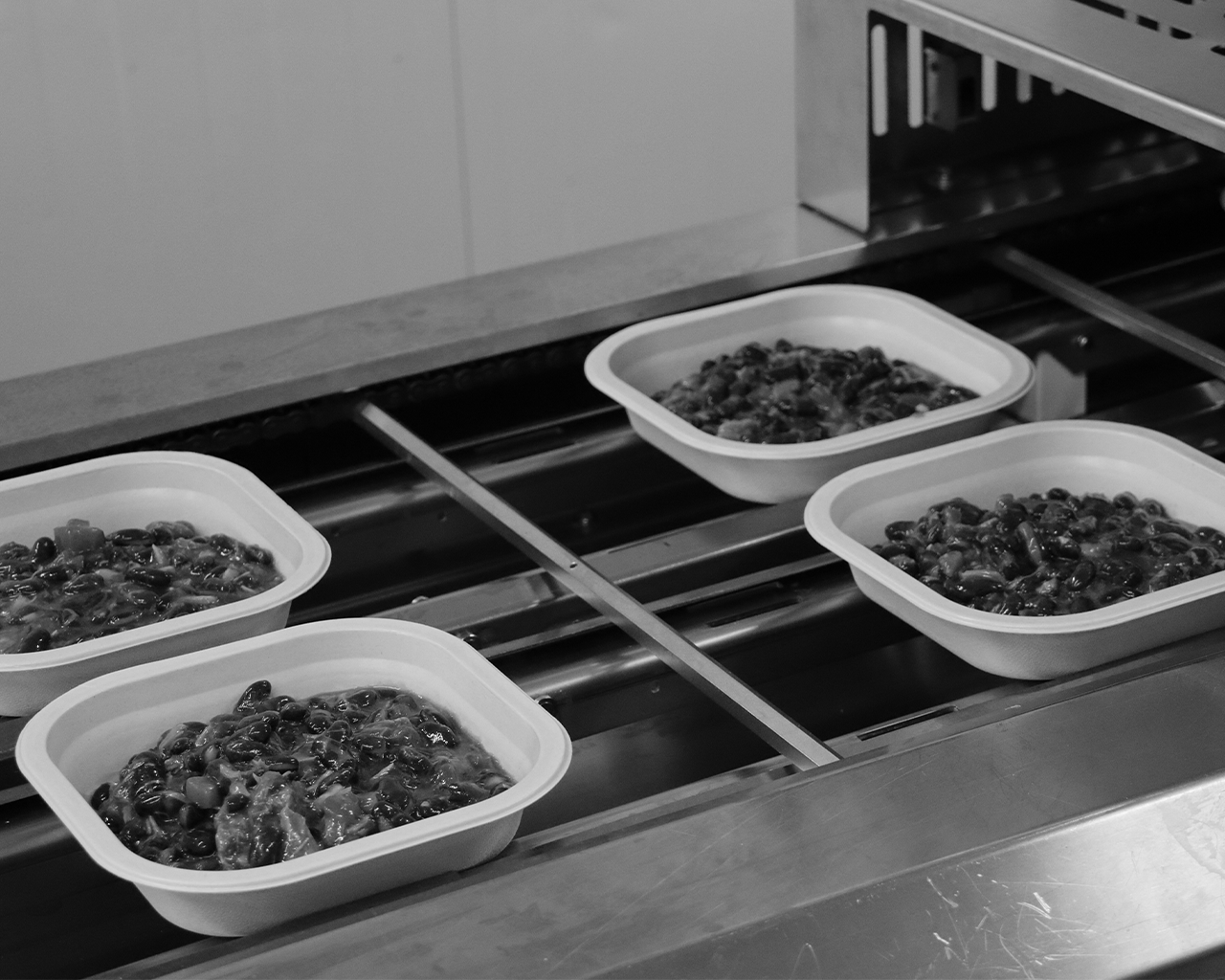 Trays with portions of food prepared on a conveyor belt during a solidarity cooking project supported by the Ferrer group.