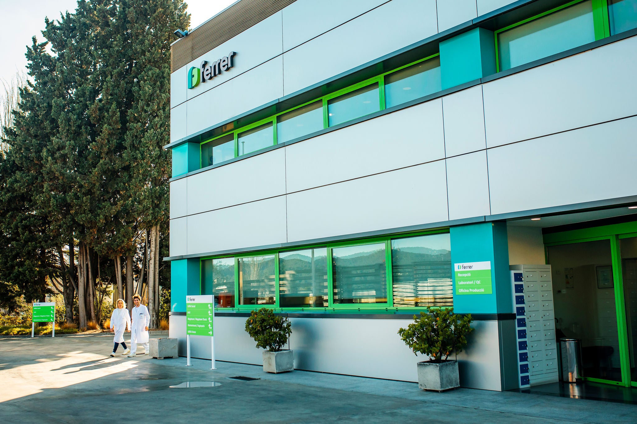 Instalaciones de Ferrer en Sant Cugat, con fachada corporativa, accesos señalizados y profesionales caminando junto al edificio.