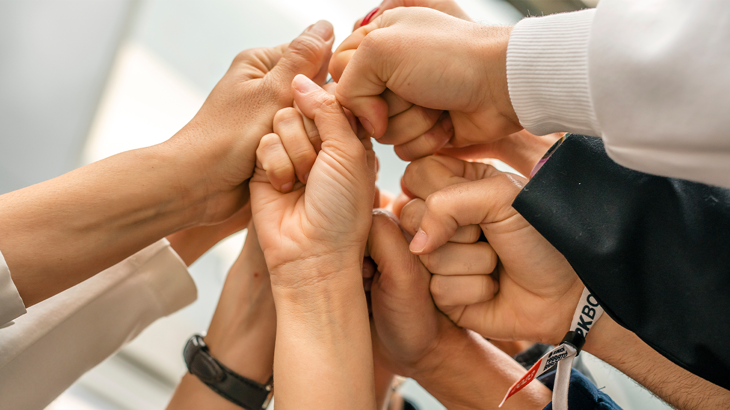 Professionals from the Ferrer group with their hands joined in a gesture of collaboration to achieve the standards of official certifications.