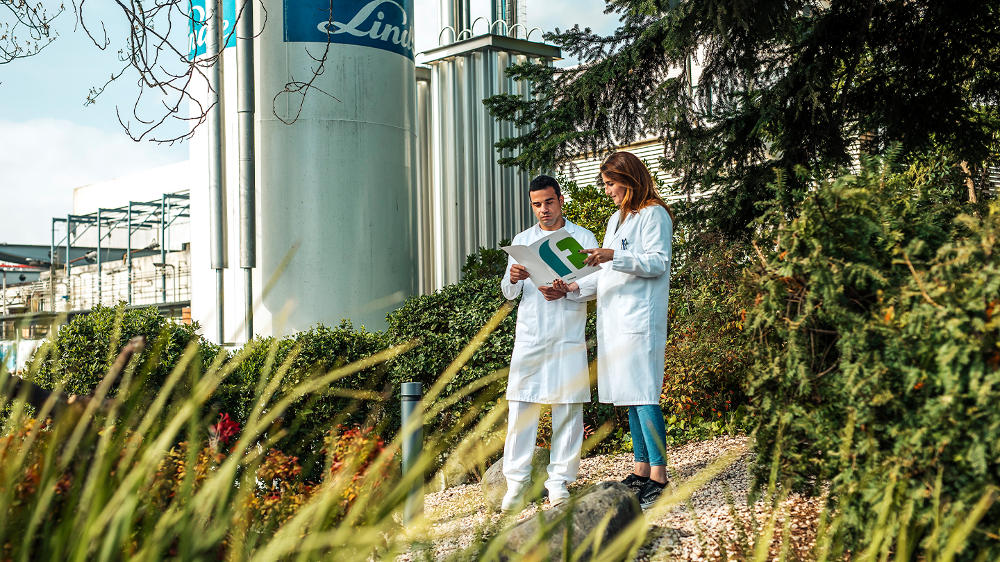 Dos técnicos en bata blanca revisando documentación sobre la fabricación de principios activos (APIs) en la planta química de Ferrer.