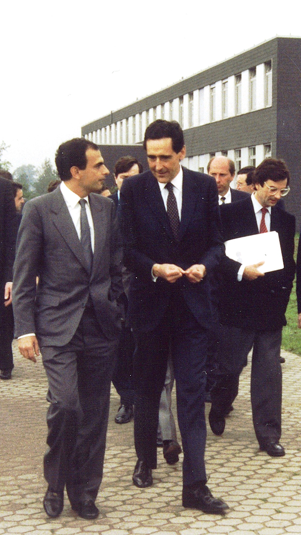 Fotografía de archivo de un grupo de hombres con trajes formales caminando y conversando en el exterior de un edificio de oficinas.
