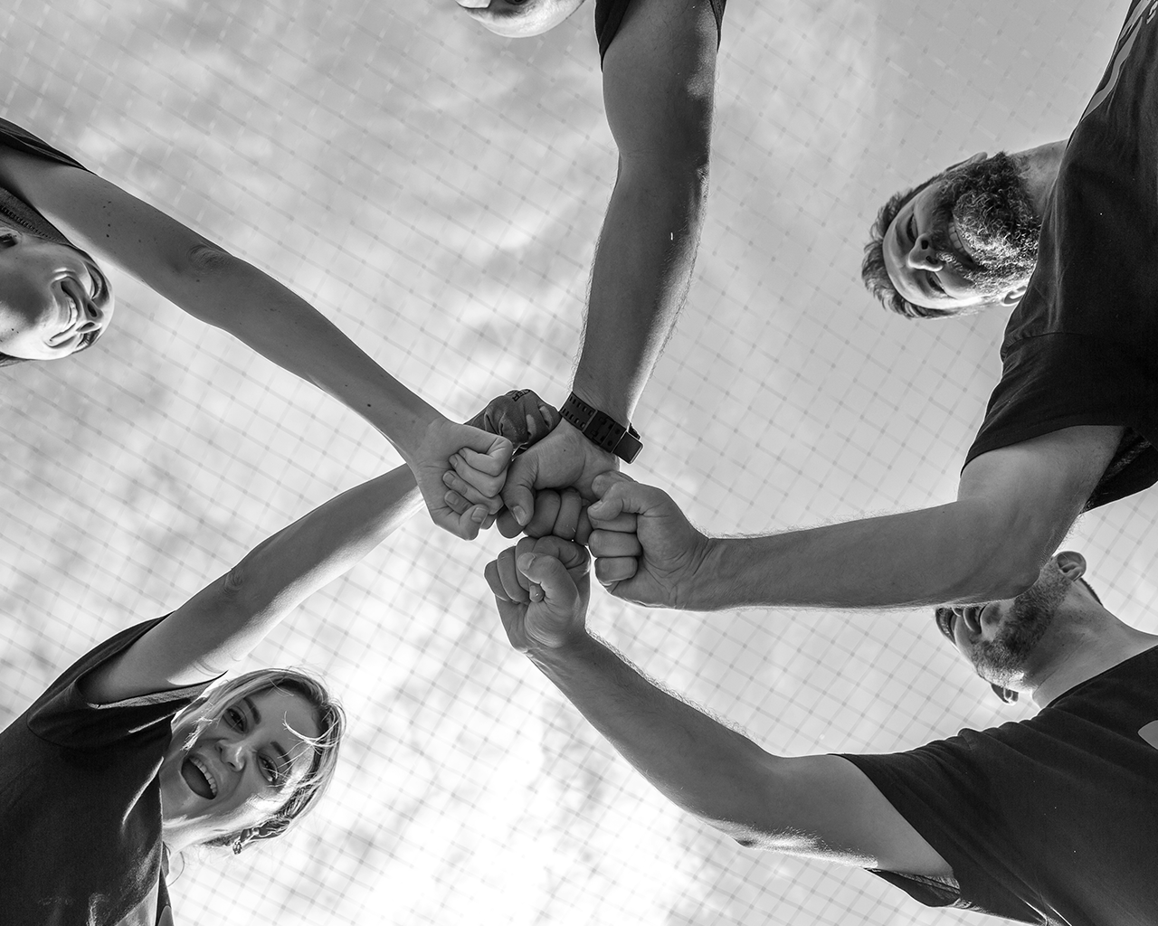 Volunteers from the Ferrer group wearing corporate T-shirts putting their fists together as a sign of success and joint collaboration.