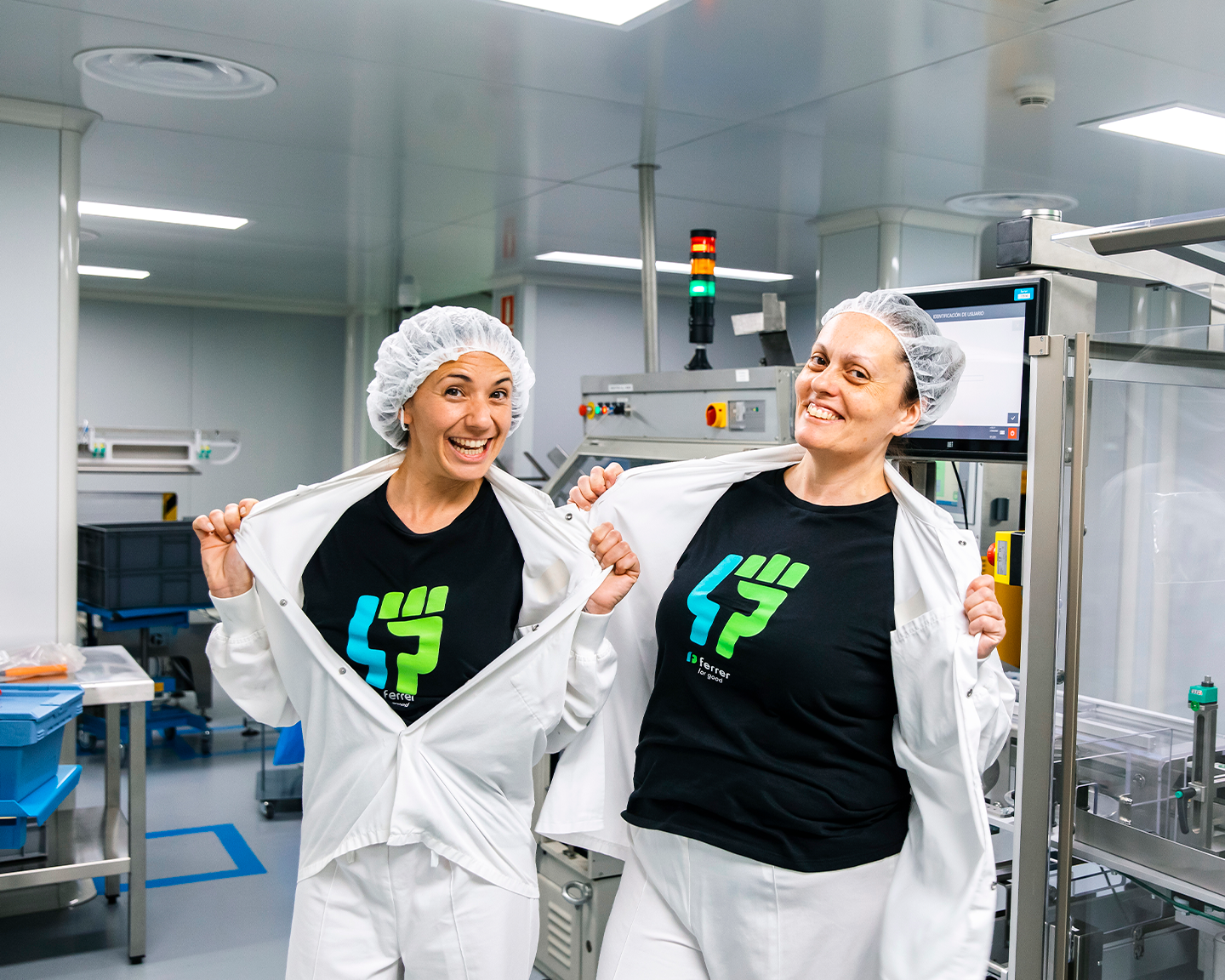 Dos operarias de Grupo Ferrer mostrando orgullosas su compromiso con el equipo Great People en la planta farmacéutica.